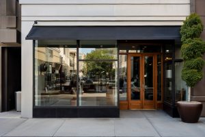 Modern storefront with clear glass windows and wooden door entry.